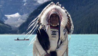 Indigenous native chief standing by the lake Louise in Canada